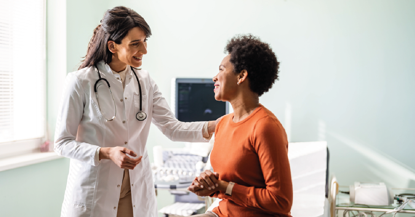 A doctor and a patient smiling and talking to one another.