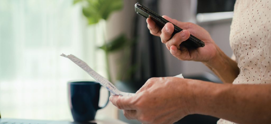 Senior woman holding a medical bill and a smartphone - choosing effective billing reminders for patients.