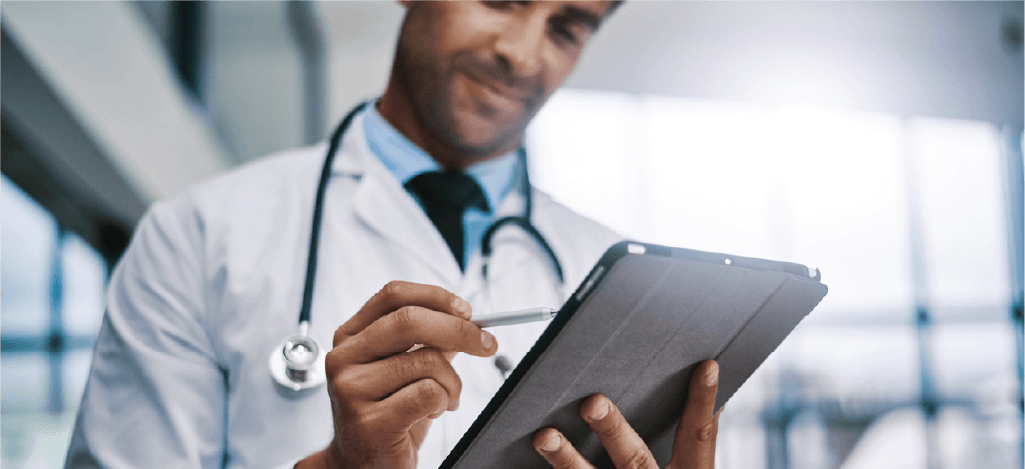 Secure patient payment plans - Male doctor using a tablet device to check patient bills.