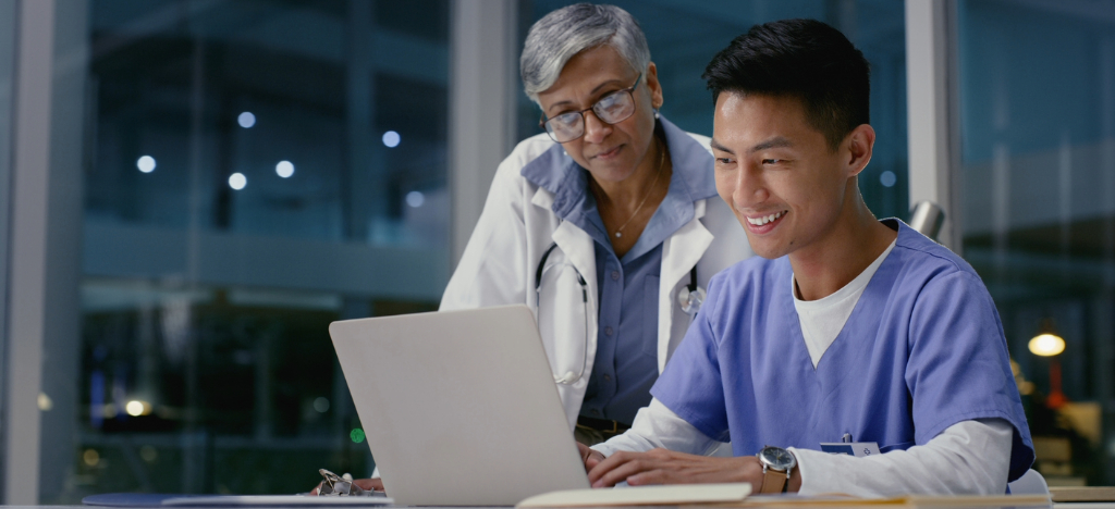 Two doctors using a laptop to check for their practice’s revenue performance.