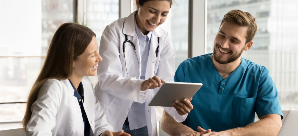 Using patient communication platforms - A group of medical professionals using a laptop and a tablet device to check their practice’s billing systems.