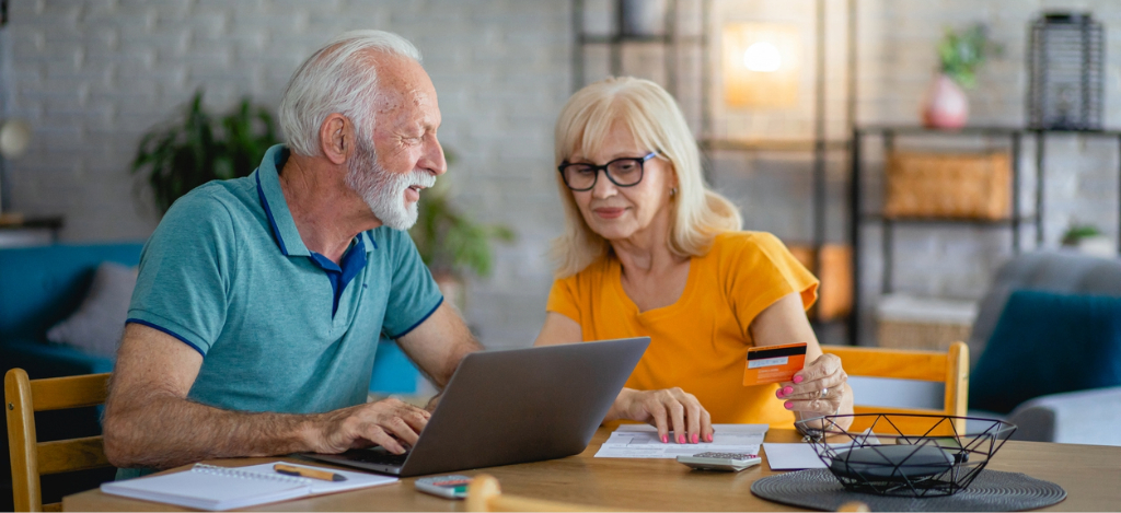 A senior couple at home using their laptop and credit card to pay for their medical bills.