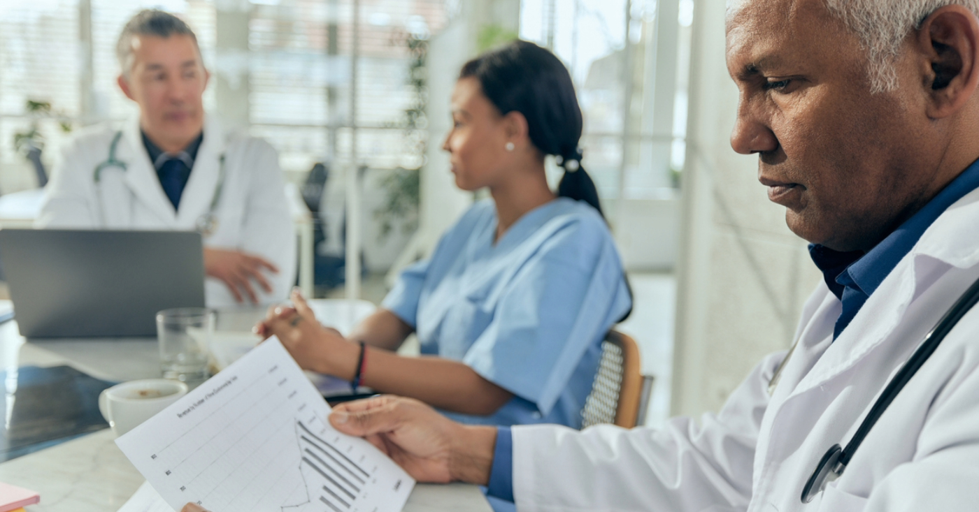 Outsourcing revenue cycle management - A male doctor checking a printed copy of their practice’s revenue.