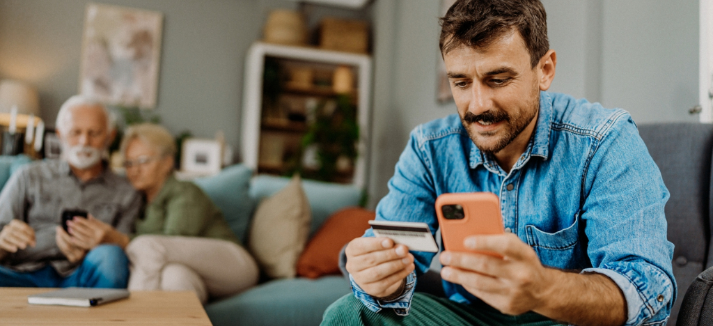 Price transparency in healthcare - A man paying his parents’ healthcare bills using a smartphone and credit card.
