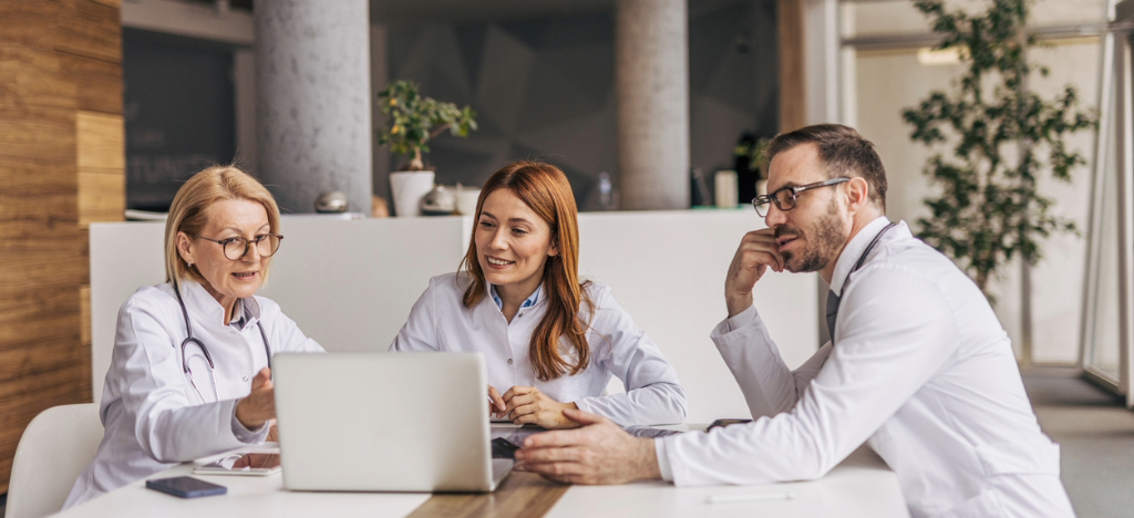 Electronic Bill Presentment and Payment - A group of doctors using a laptop while discussing improvements for their medical practice.