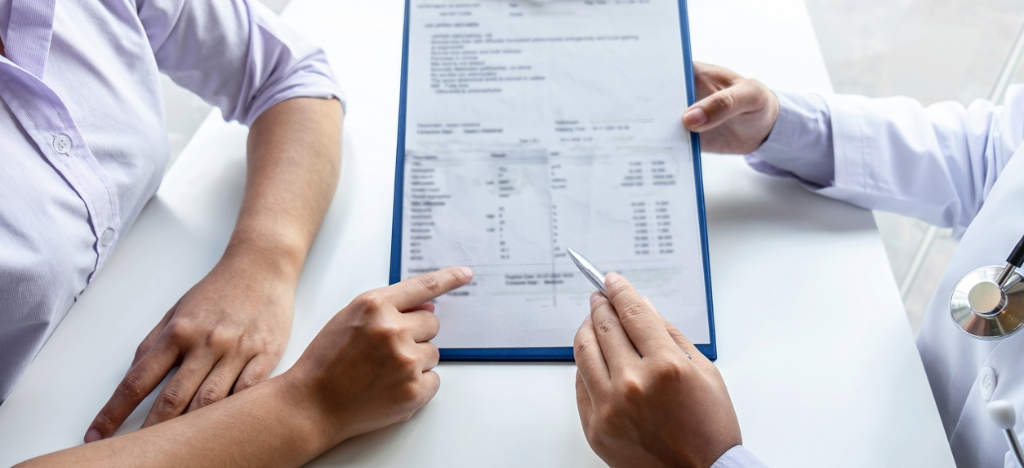 Traditional patient financing solutions - A doctor explaining a printed medical bill to his patient.