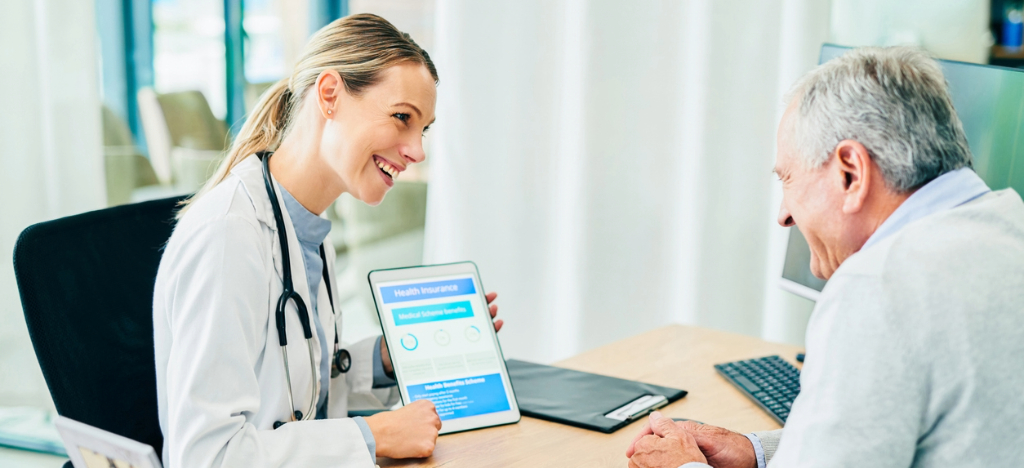 Billing software for medical practices - A female doctor using a tablet device to show financing options to her senior patient.