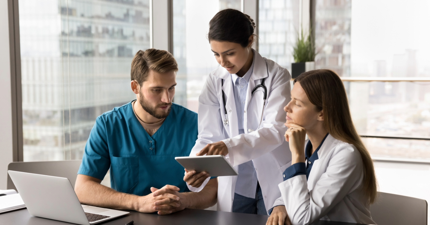 Billing software for medical practices - A group of doctors using a laptop and a tablet device to review medical billing software.