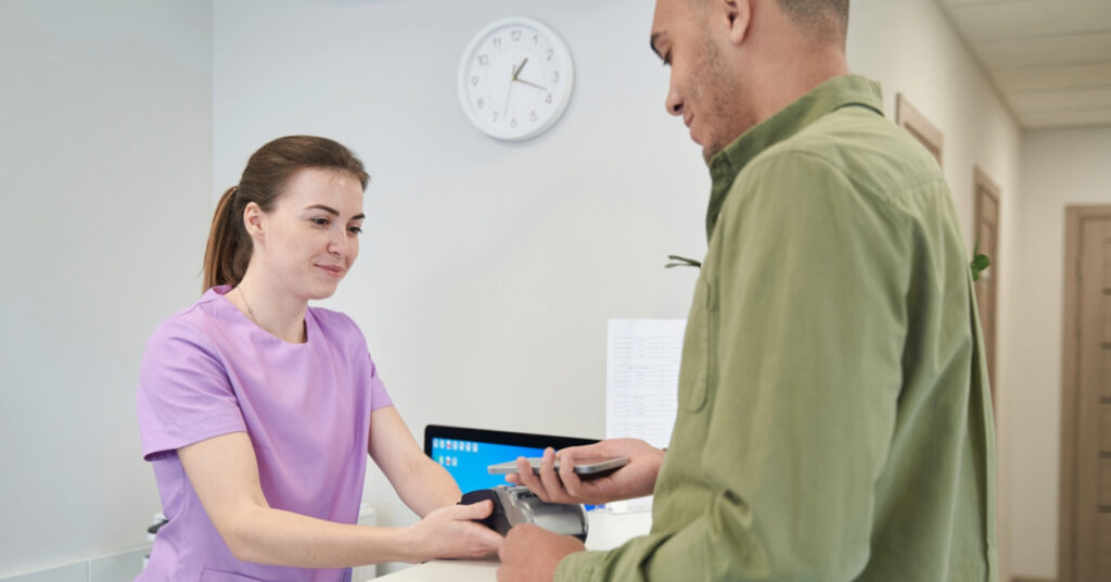 Medical office patient payments - A female hospital staff member helping a male patient pay his medical bill.