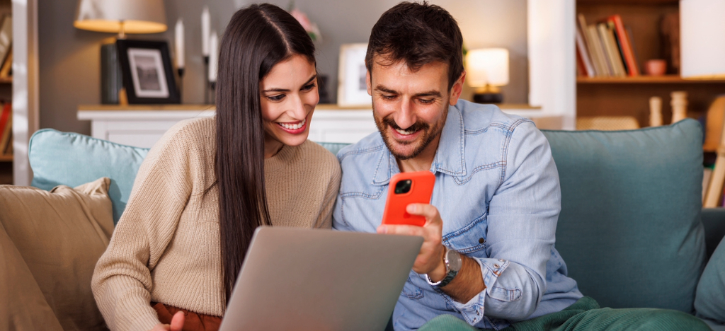 Billing strategy for practices - A couple at home using a laptop and smartphone to pay their hospital bills online.