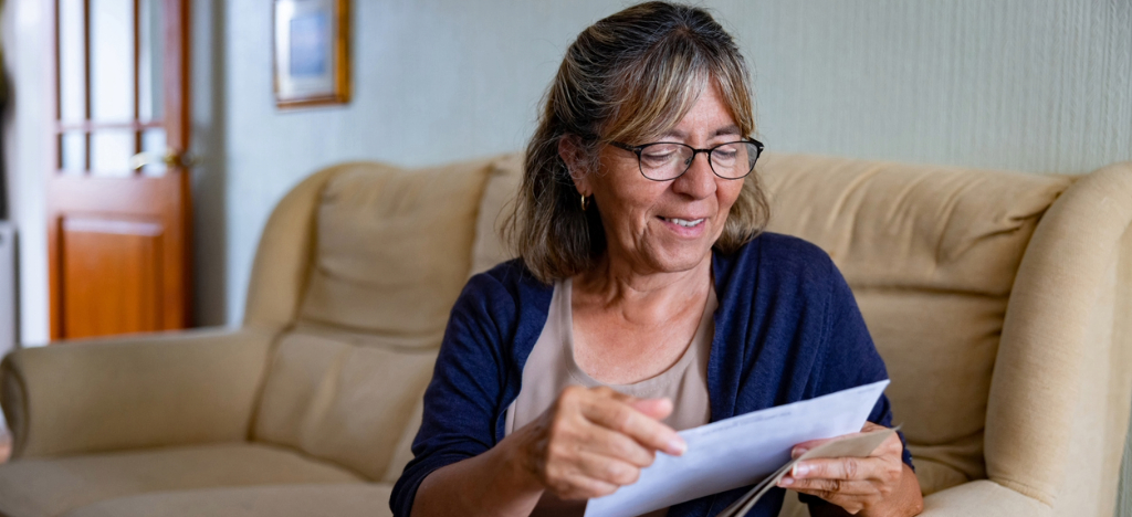 Using direct mail inserts - A senior woman reading leaflets mailed by her medical provider.