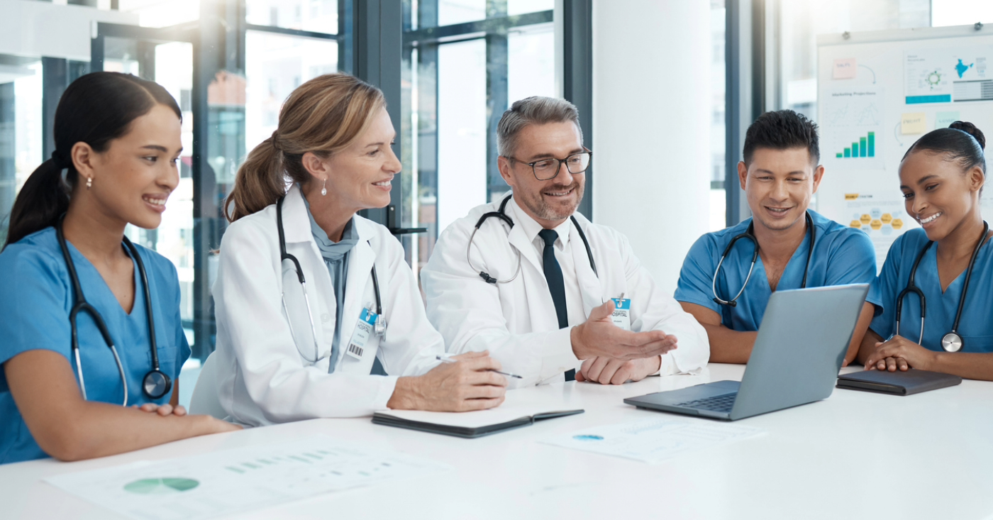 Medical office staff solutions - A team of doctors looking at a laptop while discussing how to improve practice operations.