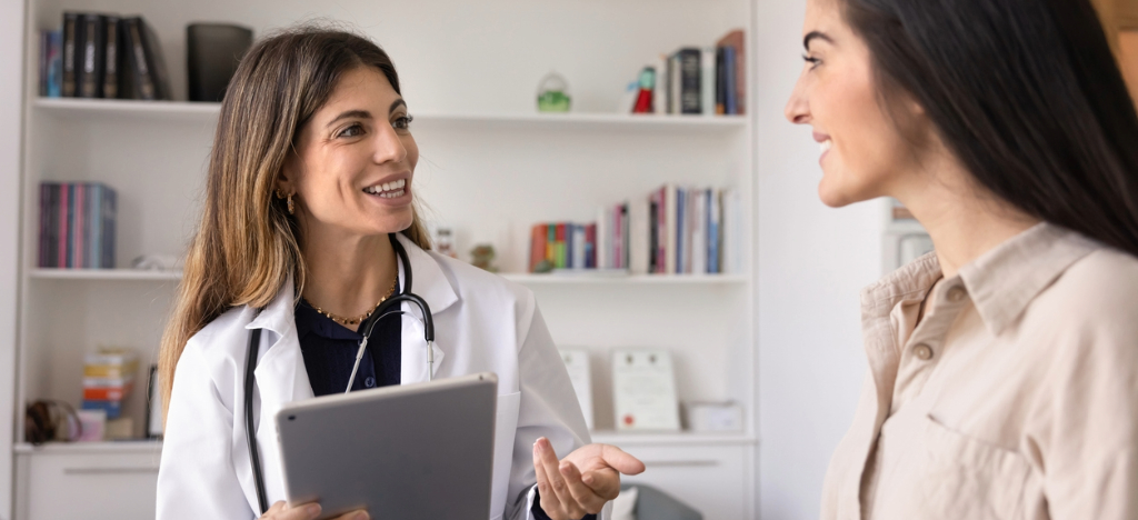 Plastic surgery clinics - A female doctor holding a tablet device while talking to her patient about financing options.