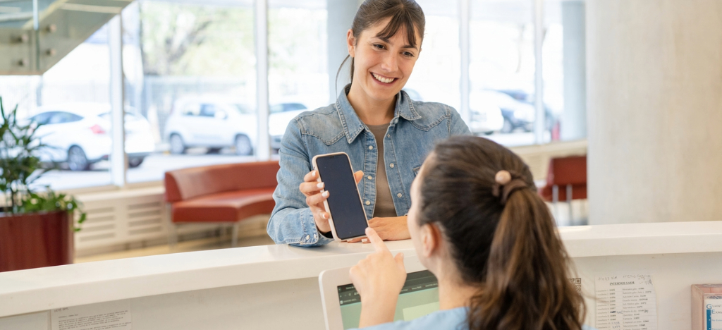 In-office payment best practices - A female patient showing her mobile hospital payment to a female hospital staff member.