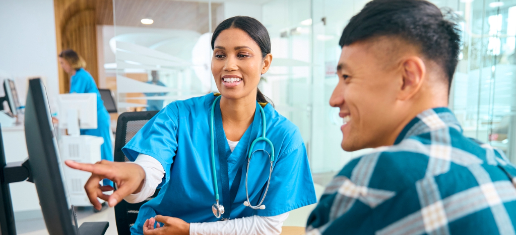 A female doctor using a computer to explain medical bills to her male patient.