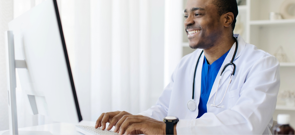 A male doctor using a computer to set automatic patient payment reminders.