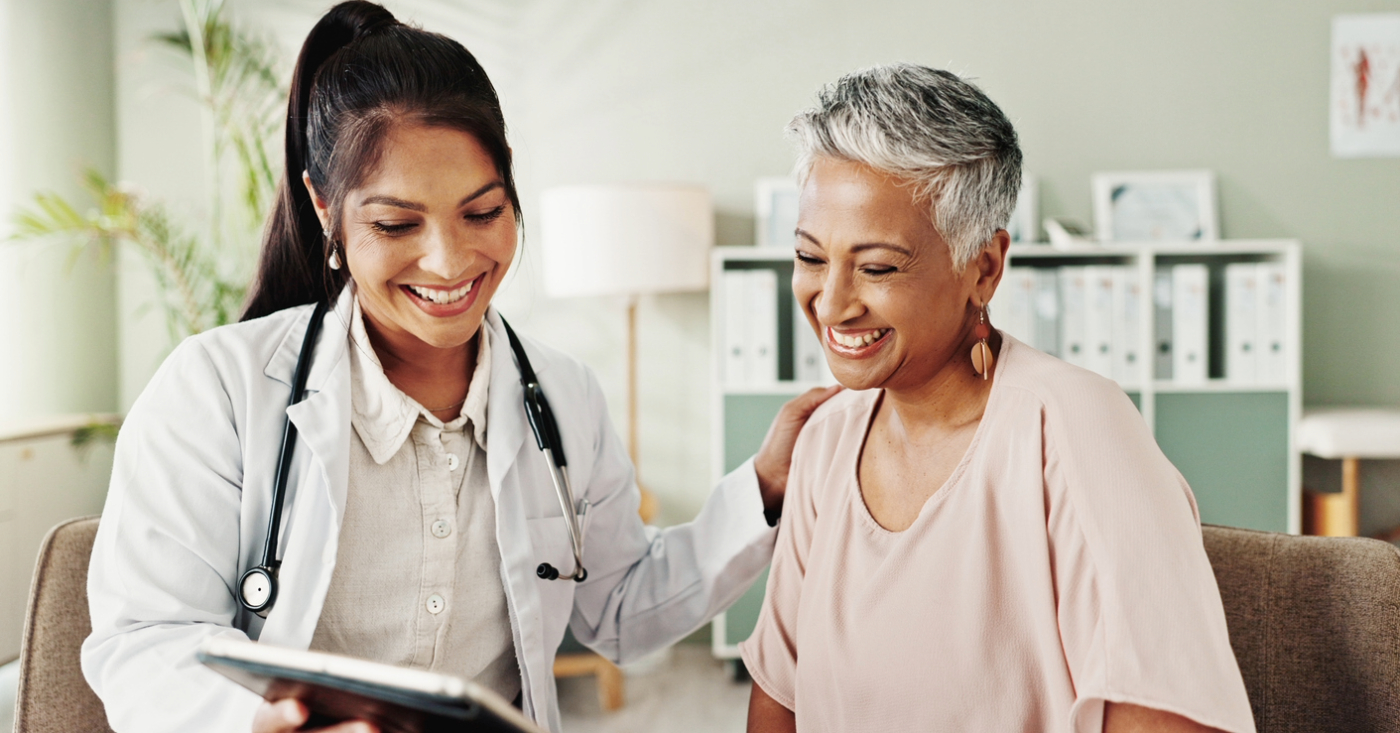 Financial health for practices - A female doctor using a tablet device to show payment plans to her senior female patient.