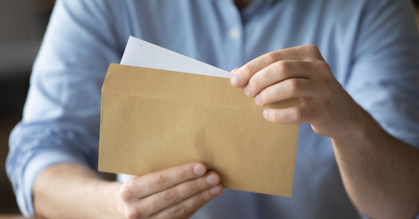 Paper statement for healthcare practices - A man opening an envelope containing his printed medical bill.