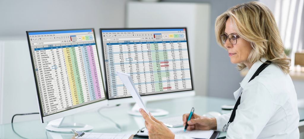 Using payment reminders - A female doctor checking her practice’s revenue through documents and online spreadsheets.