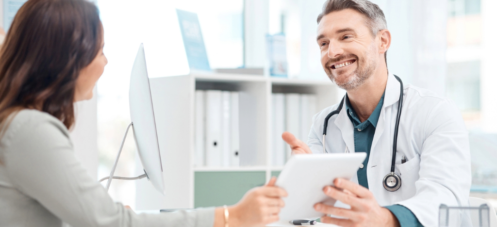 Patient billing experience - A male doctor using a tablet device to show a medical bill to his female patient.