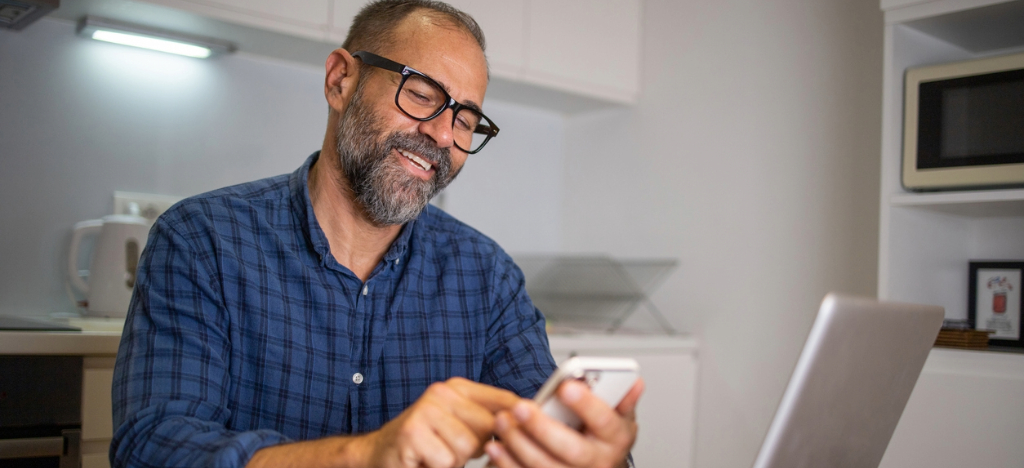 Automated payment reminders - A man at home paying his medical bill by using his smartphone.