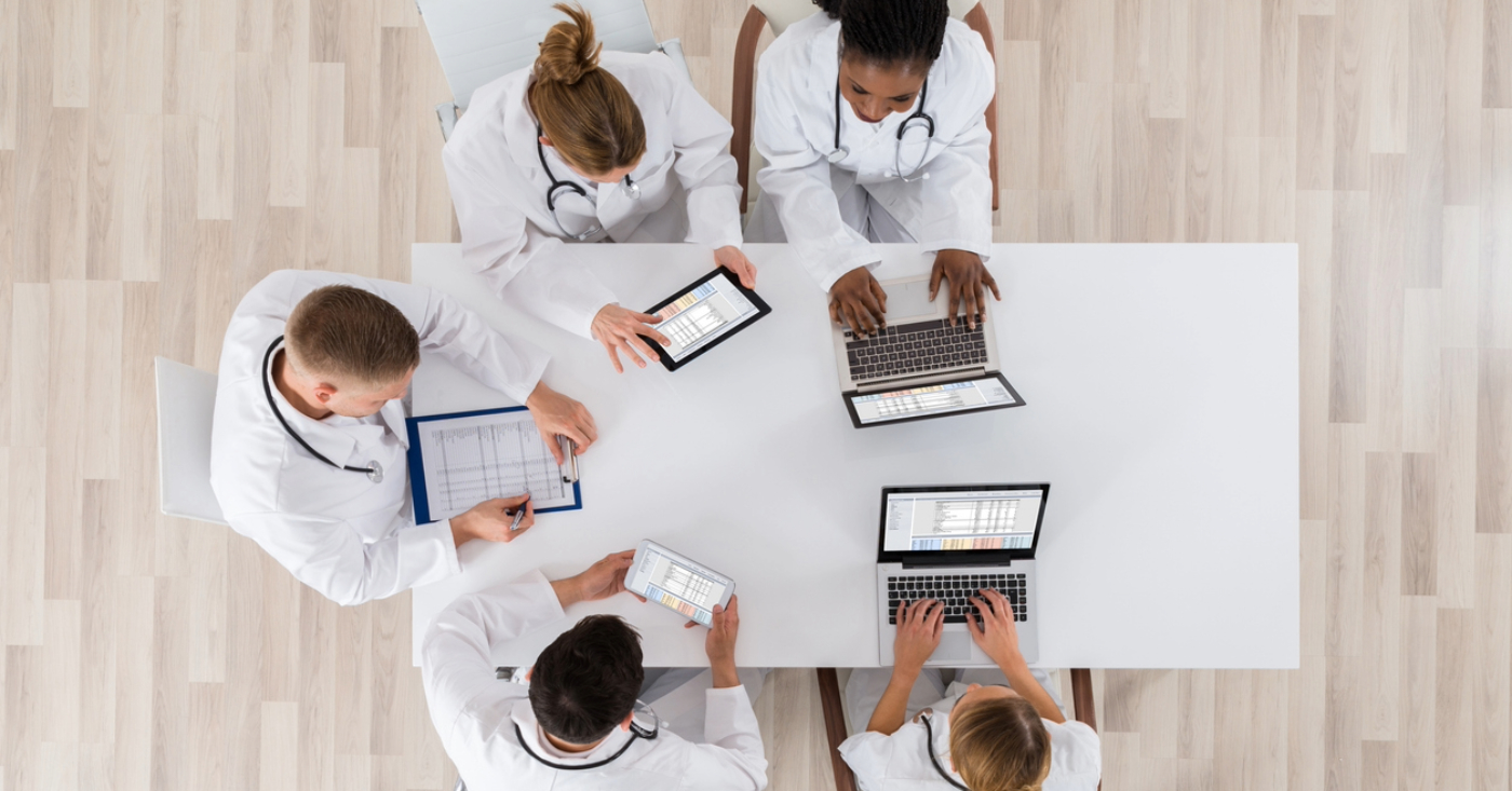 Improving medical billing systems - A team of doctors checking their practice’s revenue using laptops and tablet devices.