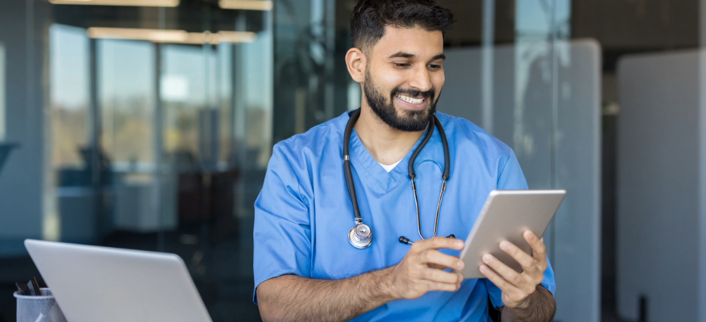 What is RCM - A male doctor using a tablet and a laptop to manage their practice’s patient bills.