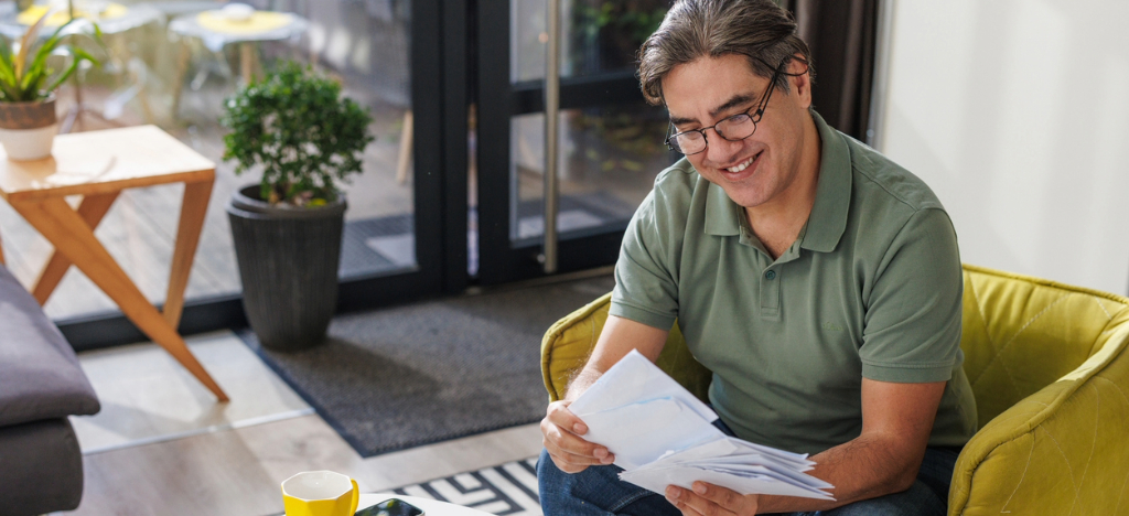 Inserts for mailed paper statement - A man opening and reviewing a mailed medical bill.