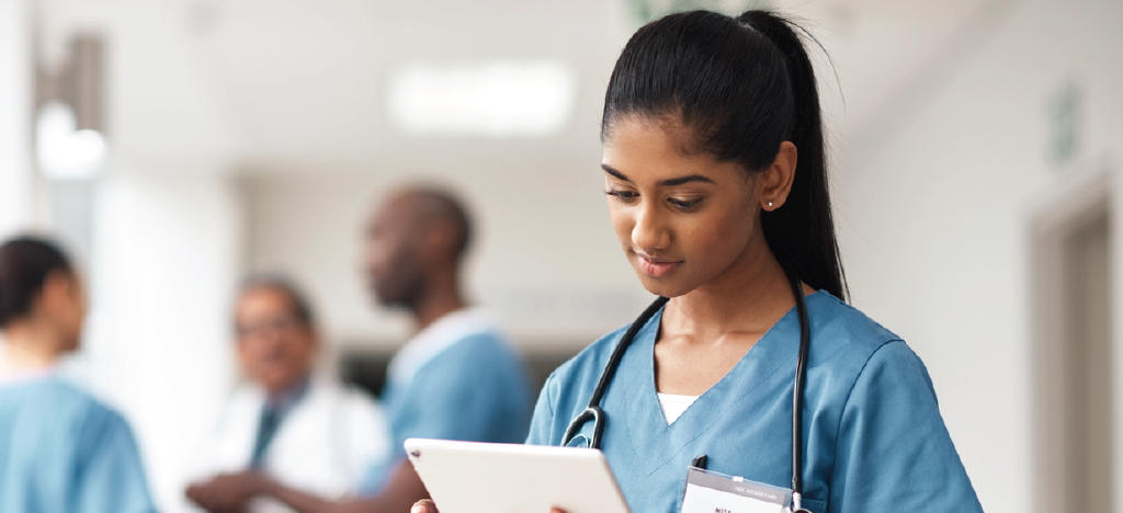 Female medical professional using a tablet device to review patient records.
