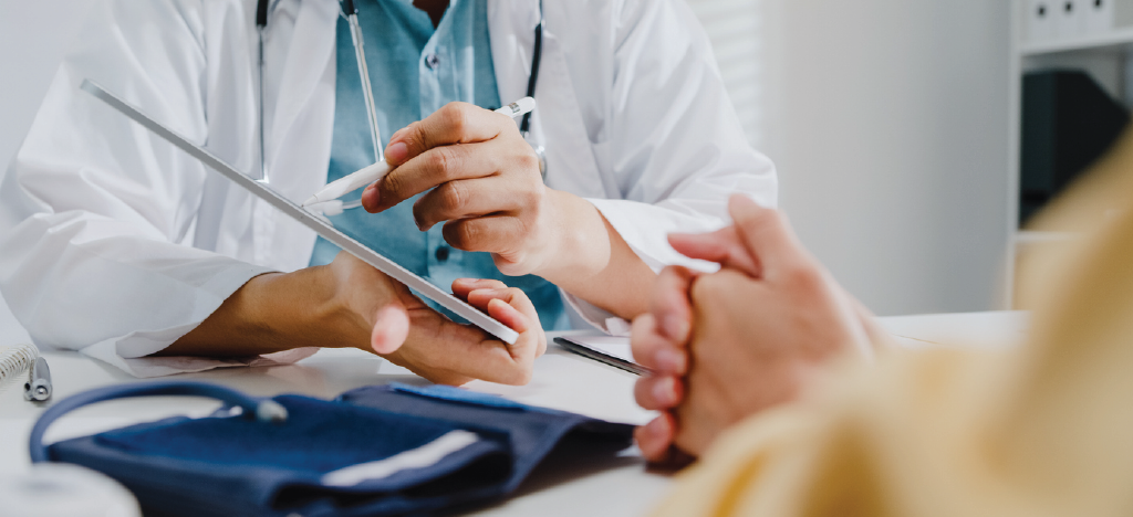 Male doctor using a tablet device to explain medical treatment to his female patient.
