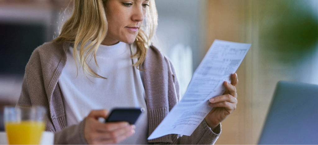 A woman at home checking her printed and online medical bill.