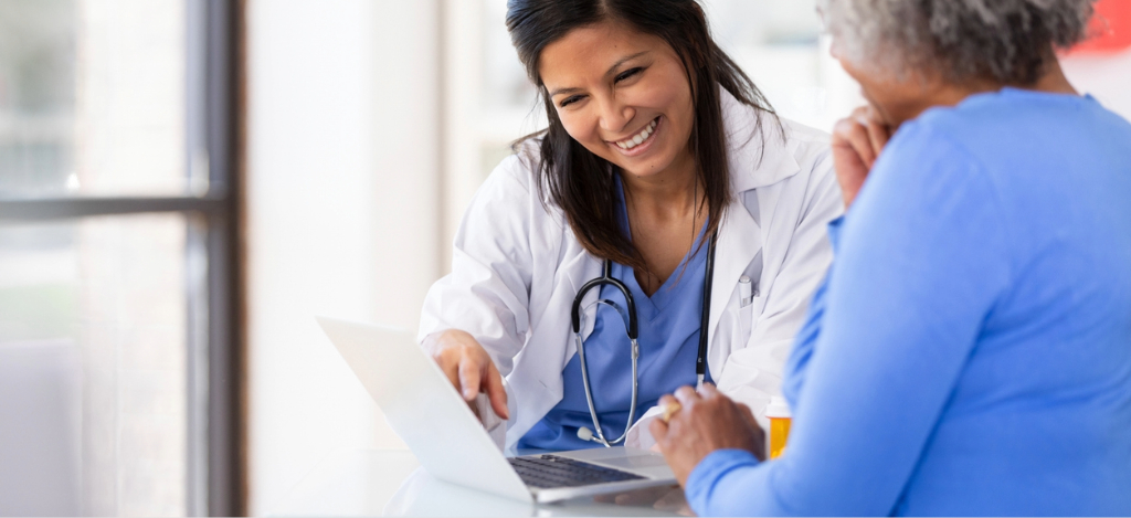 A female doctor explaining a patient’s medical bill using a laptop.