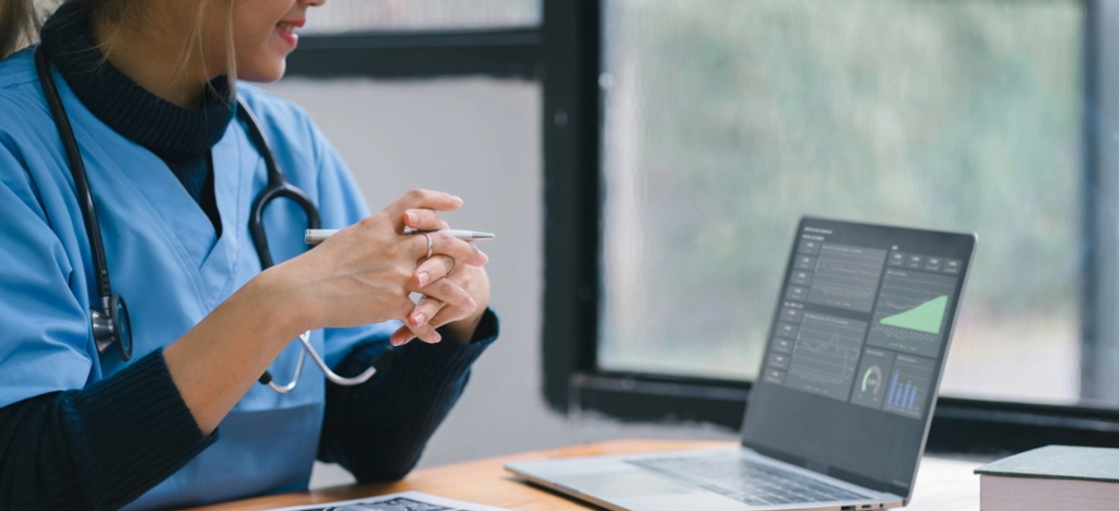 Tracking revenue cycle metrics - A female doctor looking at revenue reports on a laptop.