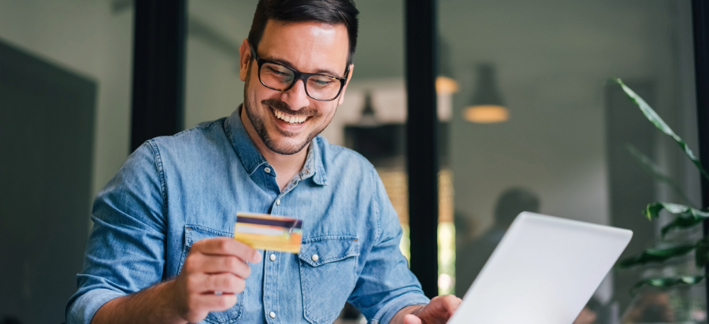 Payment strategies - A man at home using his credit card and laptop to pay his medical bills online.