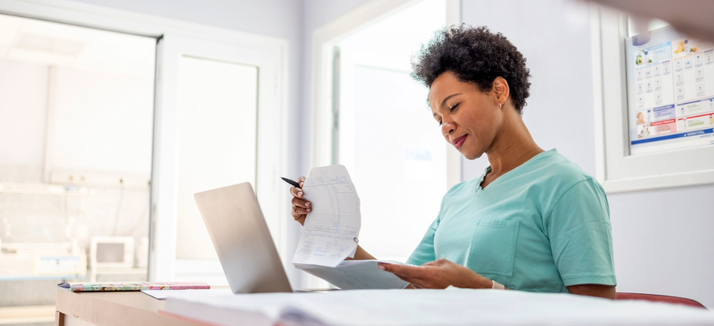 Value of a printed statement - A female medical professional reviewing printed patient bills.