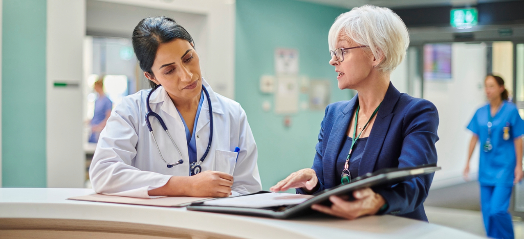 A female doctor discussing revenue processes with a female business partner.