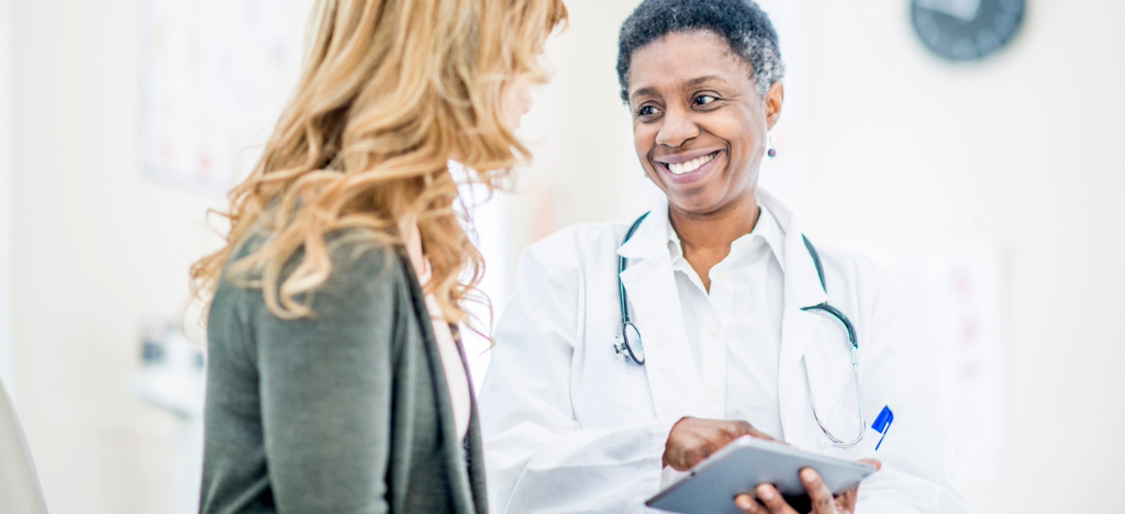 Price transparency in healthcare - A female doctor holding a tablet device while explaining medical costs to her female patient.