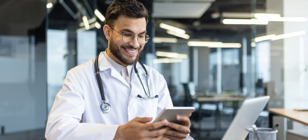 Medical office staff - A male doctor using a laptop and tablet device to access medical billing software.