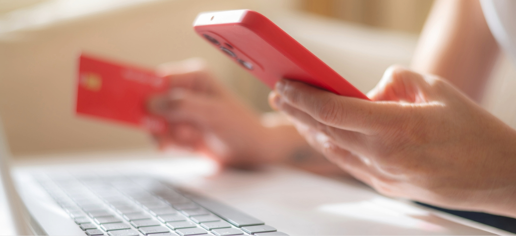 Automated patient billing - A person at home holding a smartphone and a credit card while paying for their hospital bills.