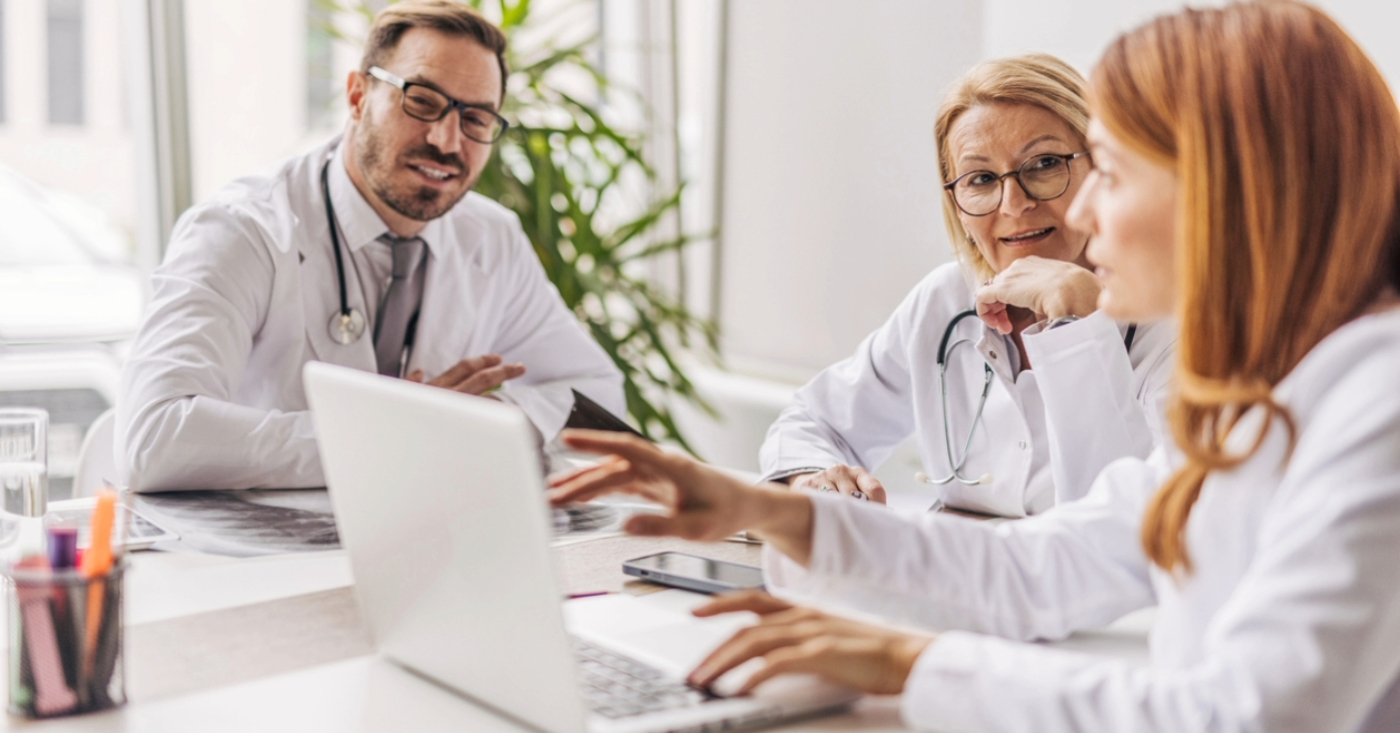 Medical billing software for small practices - A team of doctors using a laptop and discussing their use of medical billing software.