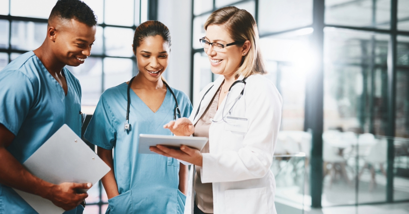 Modernizing patient financing solutions - A female doctor holding a tablet device while discussing payment solutions with her medical staff.