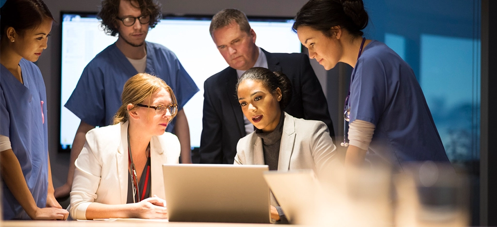 Team of doctors and business leaders in an office during a meeting - monitoring RCM regulatory changes.
