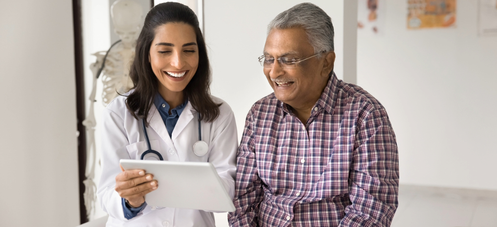 Self-payment solutions - A female doctor holding a tablet device while explaining payment options to her male senior patient.