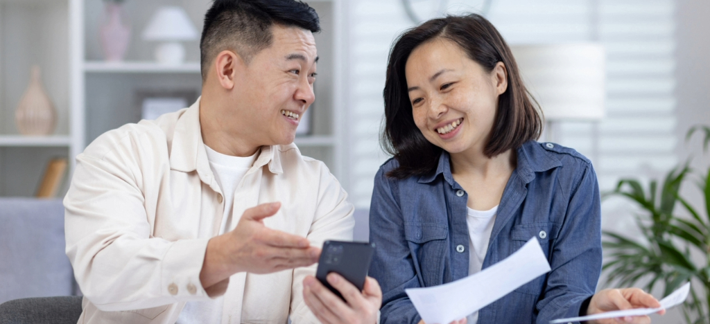 Financial health strategies - A couple at home using a smartphone to pay their monthly hospital bill.