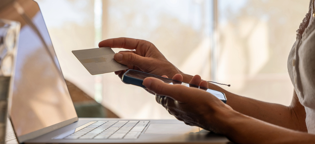 Medical office payment options - A woman using her smartphone, laptop, and credit card to pay for her medical bill.