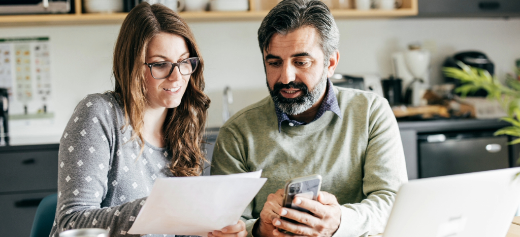 Payment strategies - A couple at home using their laptop and smartphone to check and pay for their medical bills.