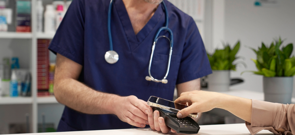 Stop chasing payments - A woman tapping her smartphone on a payment terminal to pay her medical bills.