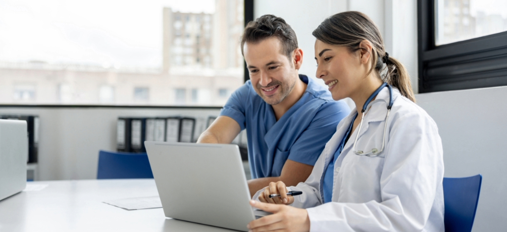 Protecting financial health - Two doctors using a laptop to review their practice’s revenue.
