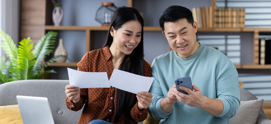 Patient financing solutions - A couple using a laptop and smartphone to manage their medical bills online.
