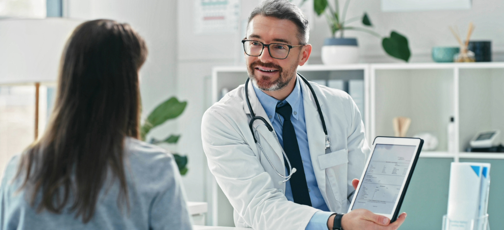 Payment strategies for practices - A male doctor using a tablet device to show his patient’s medical bill.